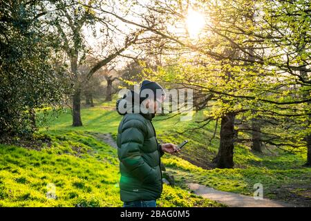 Sport im Greenwich Park. MID 40er-Mann mit Blick auf das Telefon. Stockfoto