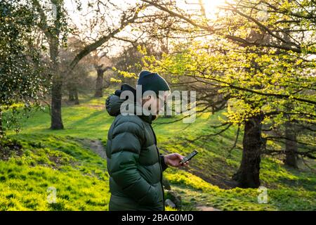 Sport im Greenwich Park. MID 40er-Mann mit Blick auf das Telefon. Stockfoto