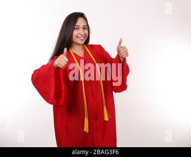 Die Frau mit dem Abschluss macht zwei Daumen nach oben. Stockfoto