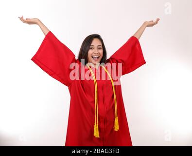 Eine aufgeregte Hochschulabsolventin wirft ihre Hände in die Luft, um zu feiern. Stockfoto