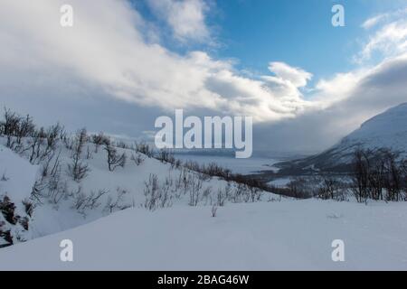 Blick von den Skipisten im Bereich des Hotel Fjallet, der tiefgefrorenen und schneebedeckten Tornetrasksee im schwedischen Lappland, Nordschweden. Stockfoto