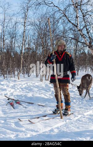 Sami man im Schnee auf traditionellen Sami-Skiern im samischen Dorf Ravttas bei Kiruna im schwedischen Lappland, Nordschweden. Stockfoto