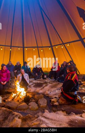 Touristen in einem Lavvu, einem Zelt, das eine temporäre Wohnung ist, die von den samischen Leuten hier im samischen Dorf Ravttas bei Kiruna im schwedischen Lapla benutzt wird Stockfoto