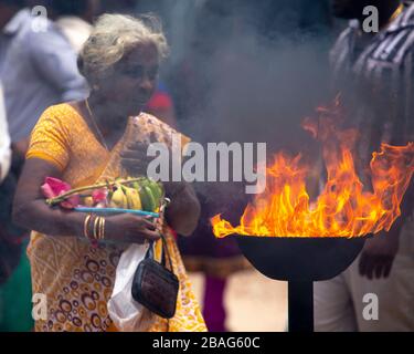 Frau neben einer Feuerschüssel im Naga Pooshani Amman Kovil Tempel auf der Nainativu Insel in der Nähe von Jaffna, Sri Lanka Stockfoto