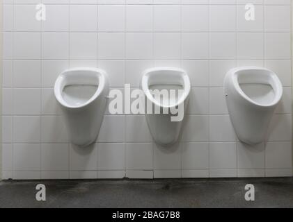 Drei Erker Männer Urinal sauber und weiß an gefliester Wand. Stockfoto