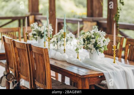 Dekorierter Hochzeitstisch für die Neuvermählten und Gäste mit Blick auf die Berge. Hochzeitsdekor und Floristik. Stockfoto