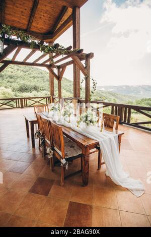 Dekorierter Hochzeitstisch für die Neuvermählten und Gäste mit Blick auf die Berge. Hochzeitsdekor und Floristik. Stockfoto