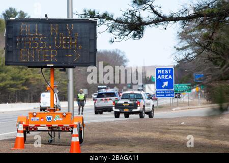 Richmond, Rhode Island, USA. März 2020. Richmond, Vereinigte Staaten. März 2020. Ein elektronisches Schild und ein Rhode Island State Trooper leiten die Personenkraftwagen mit New Yorker Kennzeichen am Freitag, 27. März 2020 in ein Rastgebiet in Richmond, Rhode Island. Die Staatspolizei und die Nationalgarde der Rhode Island Army tragen dazu bei, eine obligatorische 14-tägige Quarantäne für alle Besucher aus dem Staat New York im Rahmen der COVID-19-Antwort von Rhode Island durchzusetzen. Die Gouverneurin von Rhode Island, Gina Raimondo, kündigte die neuen Quarantänebeschränkungen für New Yorker während ihrer Pressekonferenz am Donnerstag an. Foto von Mat Stockfoto