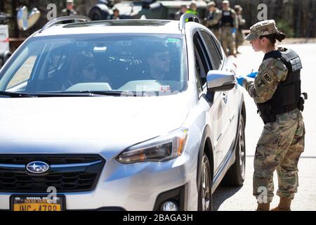 Richmond, Rhode Island, USA. März 2020. Ein Mitglied der Rhode Island Army National Guard nimmt Informationen von Menschen in einem Fahrzeug mit New Yorker Kennzeichen in einem Rastplatz in Richmond, Rhode Island am Freitag, 27. März 2020 auf. Die Staatspolizei und die Nationalgarde der Rhode Island Army tragen dazu bei, eine obligatorische 14-tägige Quarantäne für alle Besucher aus dem Staat New York im Rahmen der COVID-19-Antwort von Rhode Island durchzusetzen. Die Gouverneurin von Rhode Island, Gina Raimondo, kündigte die neuen Quarantänebeschränkungen für New Yorker während ihrer Pressekonferenz am Donnerstag an. Foto von Matthew Healey/UPI Credit: U Stockfoto