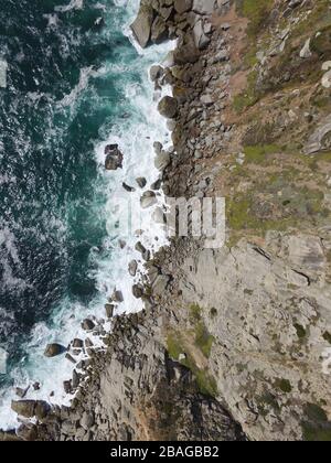 Dramatisches Luftbild der Klippe mit Wellen, die unten auf Felsen abstürzen Stockfoto