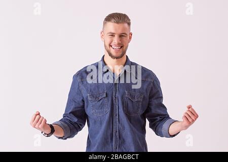 Porträt eines glücklichen jungen Mannes in Denimhemd gestisch und lächelnd, isoliert auf weißem Hintergrund. Stilvoller bärtiger Flusspferd, der positive E-Ergebnisse ausdrückt Stockfoto