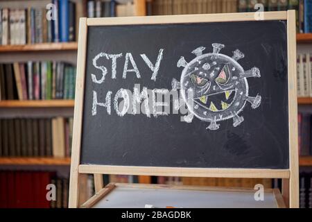 Die Aufschrift bleibt zu Hause. Warnung vor Ausbruch. Weiße Kreide auf Tafel im Zusammenhang mit der Epidemie von Coronavirus weltweit geschrieben. Covid 19-Pandemie Stockfoto