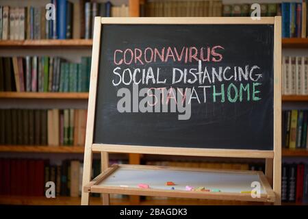 Aufschrift soziale Distanzierung bleiben zu Hause. Warnung vor Ausbruch. Weiße Kreide auf Tafel im Zusammenhang mit der Epidemie von Coronavirus weltweit geschrieben. Stockfoto