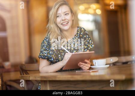 Designerin skizziert mit digitalem Tablet und Stylus im Café Stockfoto