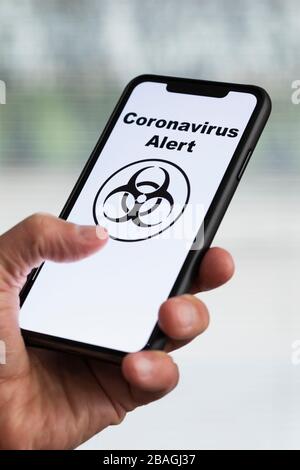 Mann hält Handy mit Coronavirus Alarm auf dem Bildschirm Stockfoto