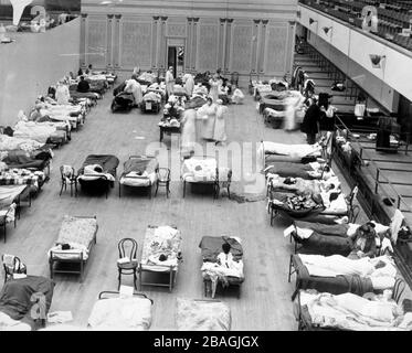 Spanische Grippe. Krankenschwestern des amerikanischen Roten Kreuzes neigen dazu, Patienten auf vorübergehenden Stationen zu grippebedürftigen, die im Oakland Municipal Auditorium, 1918 eingerichtet wurden. Stockfoto