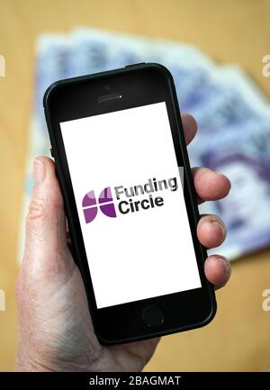 Eine Frau, die das Logo des Förderkreises auf einem Handy betrachtet. Der Funding Circle ist ein Peer-to-Peer-Kreditmarkt. (Nur redaktionelle Verwendung) Stockfoto