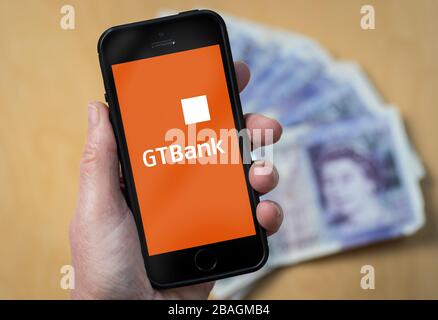 Eine Frau, die das Guaranty Trust Bank-Logo auf einem Mobiltelefon betrachtet. (Nur redaktionelle Verwendung) Stockfoto