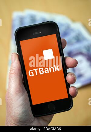 Eine Frau, die das Guaranty Trust Bank-Logo auf einem Mobiltelefon betrachtet. (Nur redaktionelle Verwendung) Stockfoto