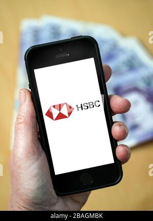 Eine Frau, die das Logo der HSBC Bank auf einem Mobiltelefon betrachtet. (Nur redaktionelle Verwendung) Stockfoto