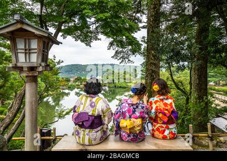 Frauen, die traditionelles japanisches Kleid tragen, sitzen auf einer Bank im Kenrokuen Garden, Kanazawa, Japan Stockfoto