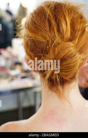 Junge Frau sitzt für Haare und Make-up mit einem chaotischen bun Frisur Stockfoto