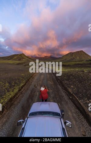 Fotograf, der den Sonnenuntergang auf den Bergen vor dem Auto fotografiert Stockfoto