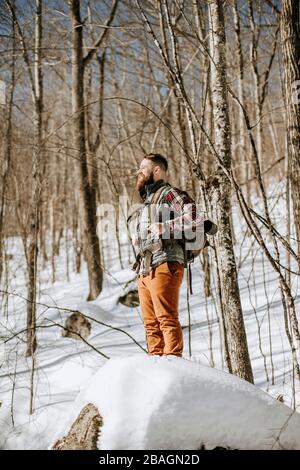 Mann mit Bart trägt Flanell steht auf Schnee bedeckt Felsen Stockfoto