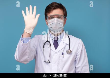 Ein Arzt in einem weißen Mantel zeigt seine Handnummer fünf auf blauem Grund Stockfoto