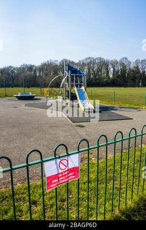 Schild auf Geländer eines Spielplatzes für Kinder in einem Park: Kein Eintritt; Spielbereich wegen Coronavirus geschlossen: St. John's Lye, Woking, Surrey, SE England Stockfoto