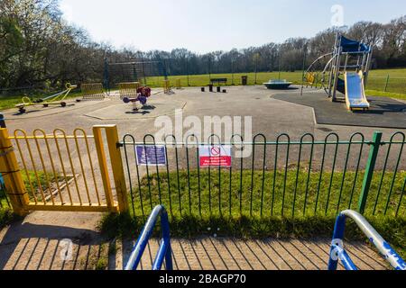 Schild auf Geländer eines Spielplatzes für Kinder in einem Park: Kein Eintritt; Spielbereich wegen Coronavirus geschlossen: St. John's Lye, Woking, Surrey, SE England Stockfoto