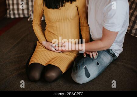 Frau erwartet Baby mit Freund. Nahaufnahme von schwangeren Frauen und Männern, die Baby-Bump halten. Stockfoto