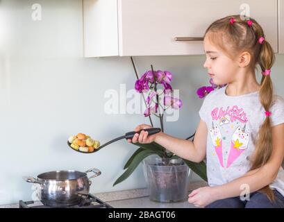 Kleines Mädchen kochende Knödel in der Küche. Quarantänekonzept für Coronavirus. Bleiben Sie zu Hause. Stockfoto