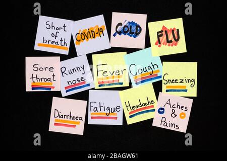Symptome von COVID-19, häufiger Erkältung und Grippe auf farbigen Haftnotizen auf schwarzem Hintergrund. Pandemieschutzkonzept. Stockfoto