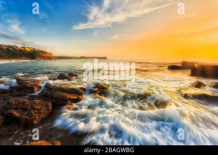 Helles Sonnenlicht über dem Meereshorizont am Warriewood Beach der Nordstrände von Sydney bei Sonnenaufgang. Stockfoto