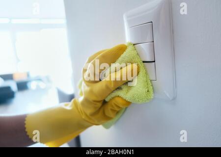 Person Mit Handschuhen, Die Lichtschalter Mit Desinfektionsmittel Desinfiziert Stockfoto
