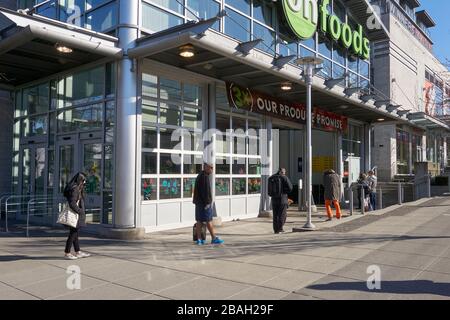 Vancouver, Kanada, 26. März 2020. Während der globalen Pandemie COVID-19 üben die Menschen soziale Distanzierung, während sie sich außerhalb eines Lebensmittelladens aufhalten. Stockfoto