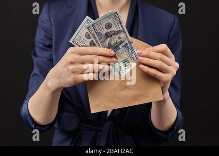 Mädchen in einer Jacke auf entfernt uns Dollar in einen Umschlag mit schwarzem Hintergrund. Nahaufnahme. Stockfoto