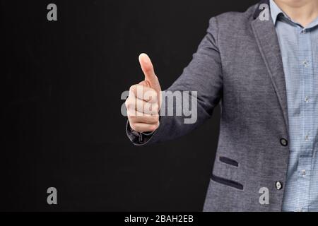 Ein Mann in einer Jacke zeigt einen Daumen nach oben als Symbol für Ähnliches. Nahaufnahme. Stockfoto