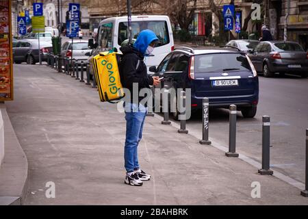 Bukarest, Rumänien - 22. März 2020: Ein Glovo Kurier für die Lebensmittelzustellung mit Maske. In Rumänien sind die Restaurants geschlossen und es sind nur Lieferungen erlaubt Stockfoto