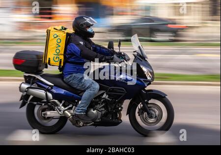 Bukarest, Rumänien - 25. März 2020: Ein Glovo-Kurier für die Lebensmittelzustellung, der Maske auf einem Motorrad trägt. Restaurants sind geschlossen, und nur Lieferungen sind zulässig Stockfoto
