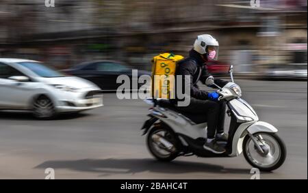 Bukarest, Rumänien - 26. März 2020: Ein Glovo-Kurier für die Lebensmittelzustellung, der eine Maske auf einem Roller trägt. Restaurants sind geschlossen, und nur Lieferungen sind zulässig d Stockfoto