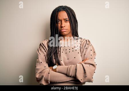 Junge afro-amerikanische Modefrau, die beiläufig über dem braun isolierten Hintergrund steht, skeptisch und nervös, missbilligend im Gesicht mit gekreuzt Stockfoto