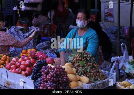 Kambodianischer tropischer Obsthändler, der während der Coronavirus-Pandemie eine Gesichtsmaske trägt und ruht. Der Kandal-Markt, Phnom Penh, Kambodscha. © Kraig Lieb Stockfoto