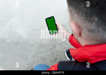 Männer Hand halten Smartphone mit grünem Display für Ihre Inhalte, Mann's Hand mit Handy mit leerem Bildschirm Stockfoto