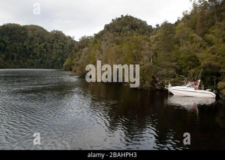 Strahan Tasmanien, Blick auf den Fluss mit einem kleinen Boot, das an einem Holzsteg angedockt ist Stockfoto
