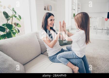 Profilfoto des hübschen kleinen Mädchens junge Mama klatscht Arme mit Spaß spielen Spiel zählen Zahlen Sitzen bequemes Sofa verbringen Sie Zeit am Wochenende zusammen Stockfoto