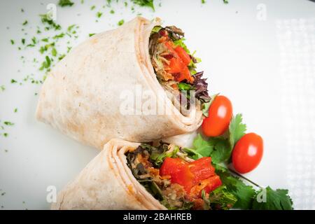 Eine frische, leckere putenverpackung auf weißer Platte mit gehackter Petersiliengarnierung Stockfoto