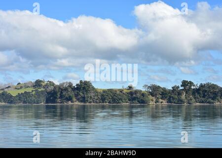 Enger Hafen mit sehr ruhigem Wasser und einer vor dem Hintergrund mit Vegetation bedeckten Hügellandschaft. Stockfoto