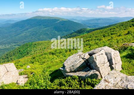 Schöne Sommerlandschaft in den Bergen. Grüne Wiese auf der Hügelseite. Blick in die Ferne unter einem blauen Himmel mit Wolken Stockfoto